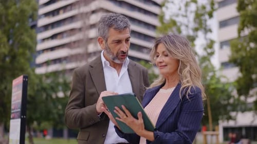 Business Colleagues Using a Digital Tablet Discussing Project Outdoors in the City