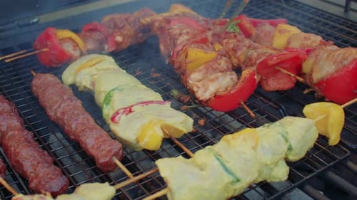 Brochettes de viande et de légumes grillés cuisant sur un barbecue enfumé.
