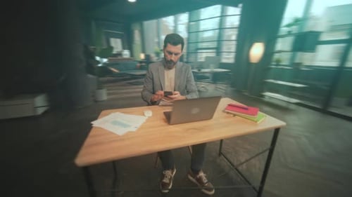 Man Works at Desk on Laptop in Office