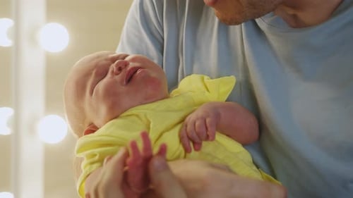 Dad Holding a Newborn Baby in His at Home
