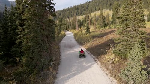 Aerial shot behind an atv driving on dirt roads in the mountains of Utah.