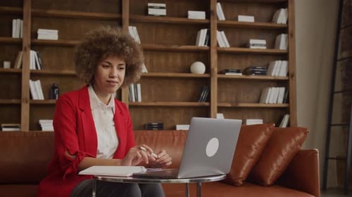 Woman Making Notes Speaking on Video Call Using Laptop