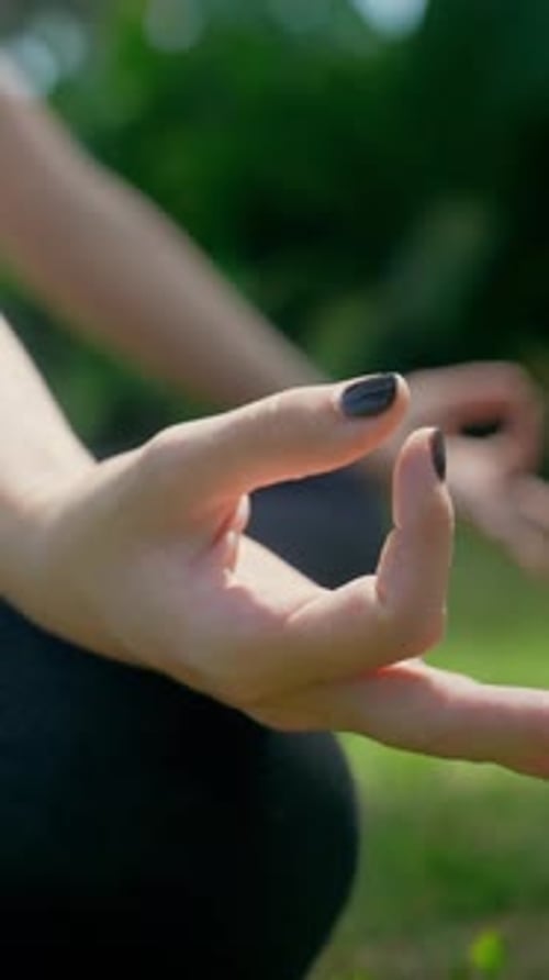 Sporting Woman Doing Yoga Exercises and Breath Meditation Sitting on Green Grass