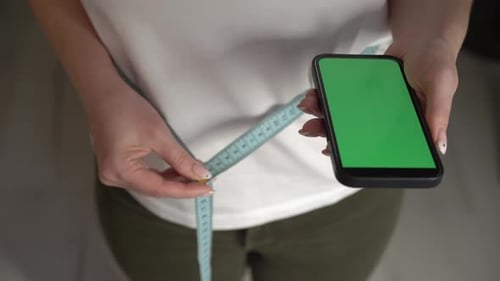 Adult Holding Measuring Tape and Cell Phone with Green Screen