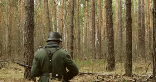 Men in Uniforms Walk in a Forest with Rifles