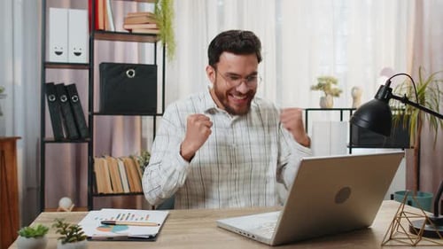 Man Celebrates Success at Home Office Desk