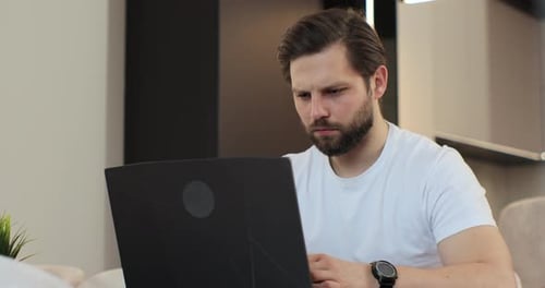 Man with Headache Working from Home on Laptop