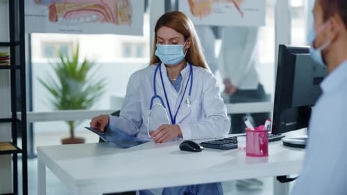 Woman doctor showing x-ray image to patient