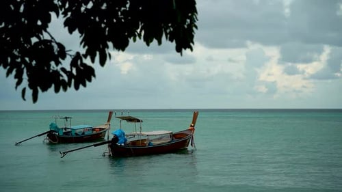 Two Thai Wooden Boats with Motors are Anchored in a Blue Bay