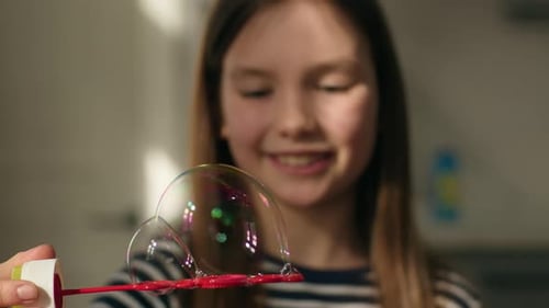 Petite fille caucasienne en gros plan tenant des bulles de savon colorées, jouet brillant, divertissement pour enfant et fille