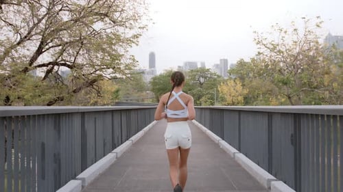 Young fitness woman in sportswear jogging in city park