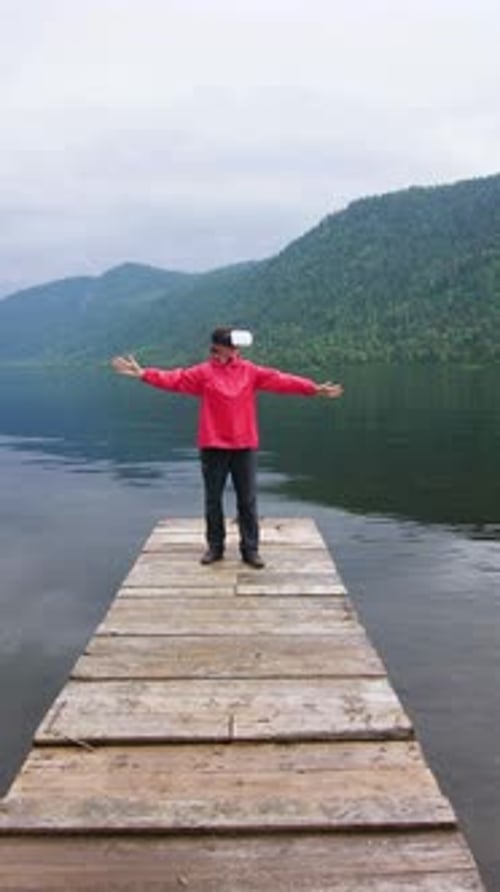 Man Enjoying the Tranquility of the Lake on a Wooden Dock Surrounded By Mountains