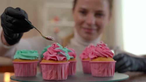 Woman Decorates Colorful Cupcakes with Sprinkles