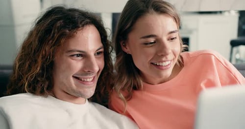 Smiling Couple Using Laptop on Sofa