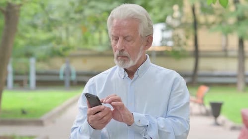 Senior Man Using Smartphone in Urban Park