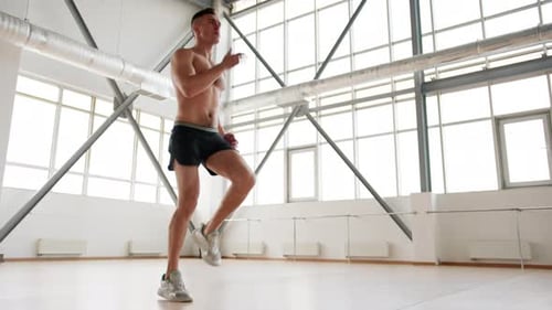 Good Looking Male Athlete Training His Muscles in a Bright Sport Studio