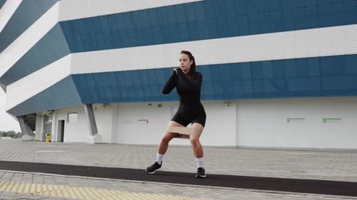 Woman Training with Resistance Band in Front of Modern Stadium