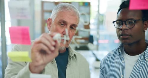 Two Men Brainstorming Ideas Writing on Glass Wall