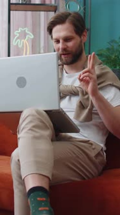 Man Sitting on Couch Talking on Laptop