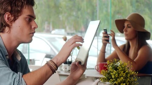 Medium Shot Of Casually Dressed Man Using Touch Screen Tablet Computer In Cafe.