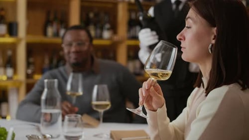 Young Woman Enjoying Aroma of White Wine at Restaurant Dinner