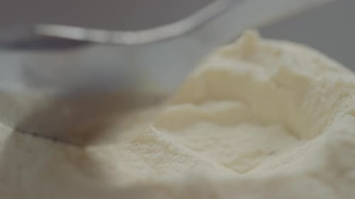 Close-up view of spoon filling with powdered milk for delicious recipes