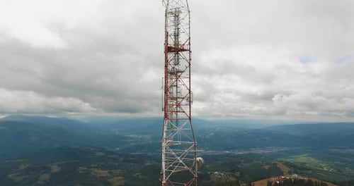 High altitude telecommunication tower holding multiple antennas, over a mountain landscape with dist