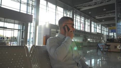 Young Happy Businessman Talking on Phone at Airport with Sun Flare at Background