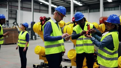 Gemischtrassige Ingenieure arbeiten in einer Einrichtung für Roboterautomatisierung - Industrierobotertechnologie