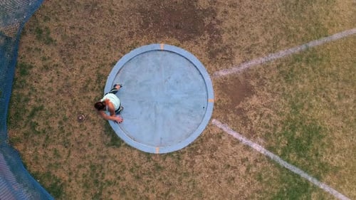 Top down view as female athlete throws discus at track and field event
