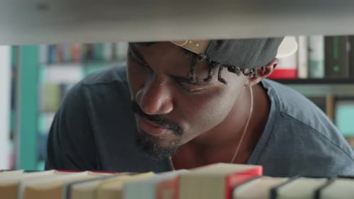 Close Up of Man Browsing Bookshelf in Library
