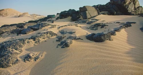 Close up shot of a white fine sand on the beach. Golden sand motion, textured black volcanic stones