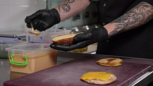 Chef Adding Sauce to Burger in Restaurant Kitchen