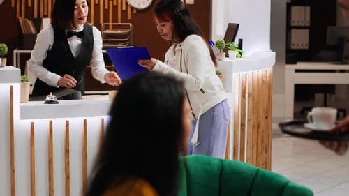 Hotel Guest Signing Registration Papers at Front Desk