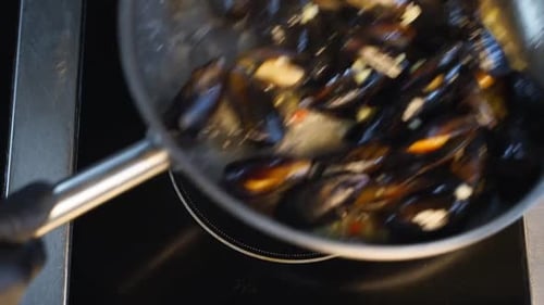 Cooking Delicious Fresh Mussels on Hot Pan in Luxury Restaurant Chef Shakes and Mixes Mussels and