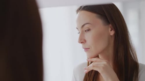 Woman Examines Face in Mirror