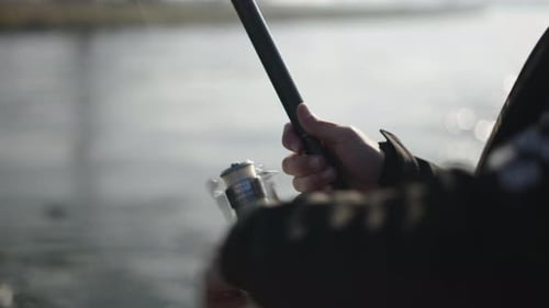 Eine Angelschnur wird von den Händen eines Fischers abgewickelt