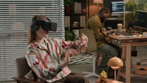 Woman Using AR Goggles when Male Colleague Developing on Computer at Office