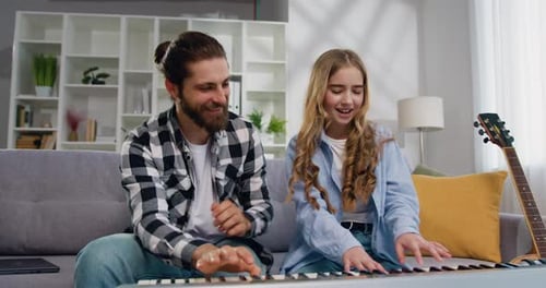Bearded Man and Teen Girl Play Piano Together