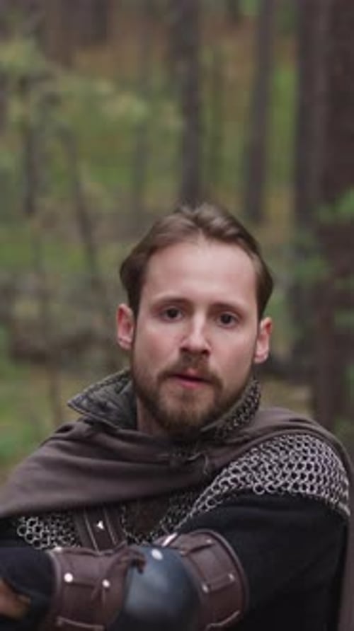 Strong Knight with Mail and Cape Strikes By Sword in Forest