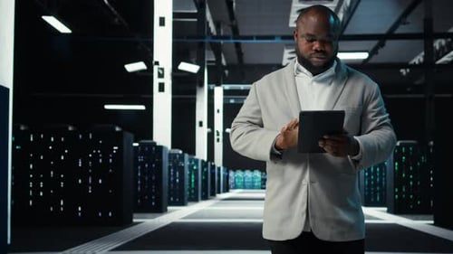 System Administrator Walking in Data Center Analyzing Infrastructure Performance