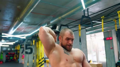 Muscular Man Lifting Dumbbell in Bright Gym