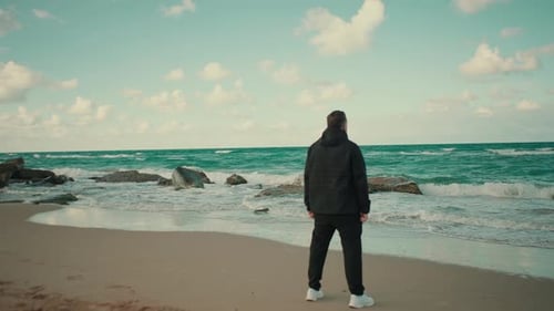 A Man standing in a beach of beautiful ocean and looking to the sea