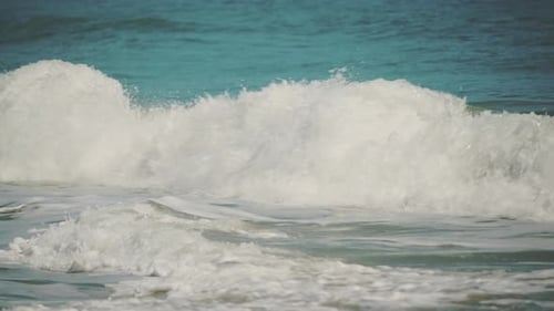 Slow Motion shot of Beautiful Blue Giant Ocean Wave Crashing at golden sandy beach
