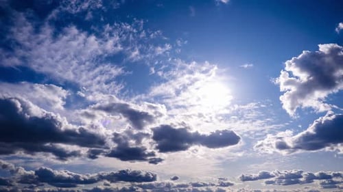 Zeitraffer von Cumuluswolken, die sich am blauen Himmel gegen die Sonne bewegen