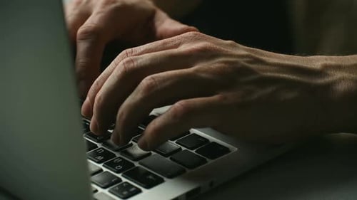 Close Up of Male Programmer Hands Typing on a Laptop Keyboard at Night