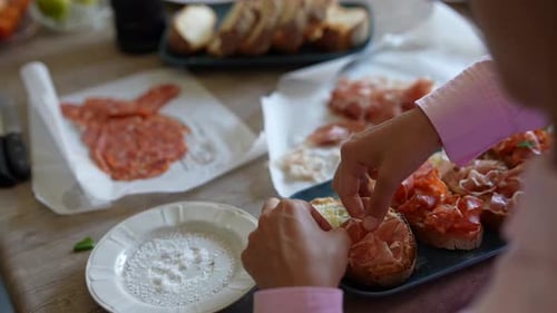 Person Prepares Bruschetta with Sliced Meats