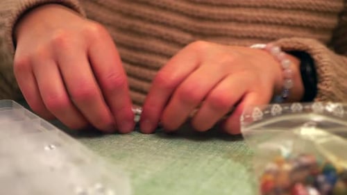 Hands Crafting Beaded Bracelet with Scissors