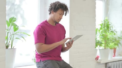 Young Adult Using Tablet by Bright Window