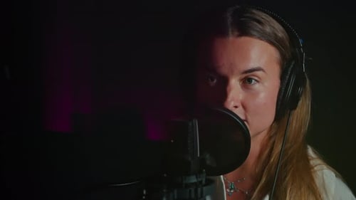 Young Woman Singing into Microphone in Studio